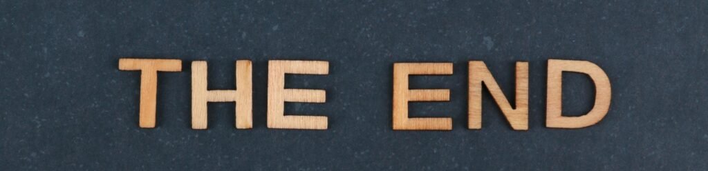 The image displays the phrase 'The End' spelled out in wooden letters against a dark background.